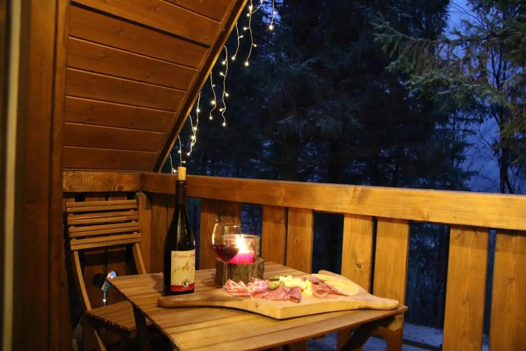 Balkon z vinom, narezkom in lučkami nad gozdom
